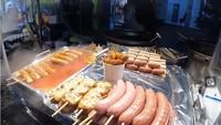 Penjual gyeran ppang ini juga menjual jajanan lainnya. Seperti sate sosis, sate tteokbokki, dan ayam goreng Korea berbumbu pekat. Foto: YouTube Nex & Veve