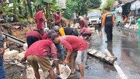 Petugas membersihkan material tembok tanggul sungai yang ambrol (Deny Prastyo Utomo/detikJatim)