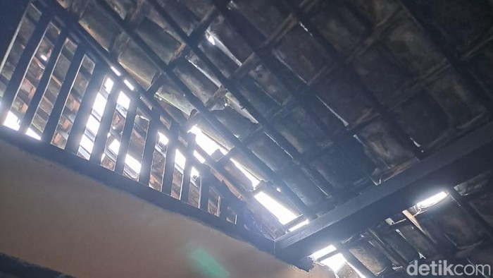 Petugas memeriksa atap MTs dan rumah warga yang rusak tersapu angin kencang di Kota Batu