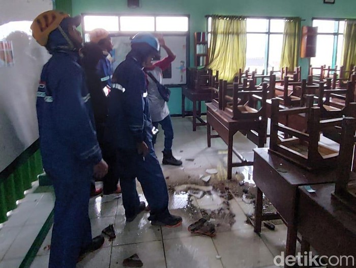 Petugas memeriksa atap MTs dan rumah warga yang rusak tersapu angin kencang di Kota Batu