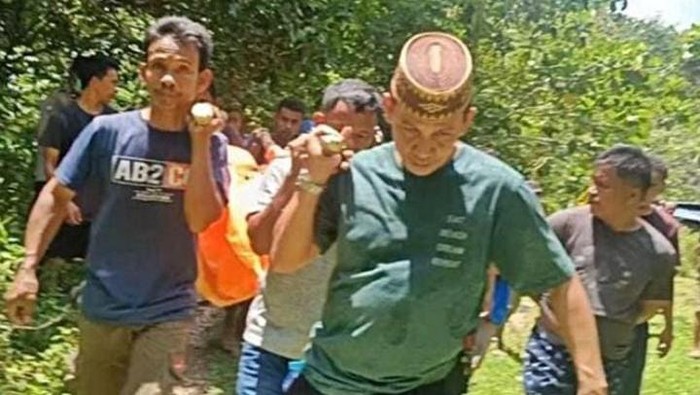 Warga mengevakuasi mayat yang ditemukan tergeletak di bawah pohon aren.