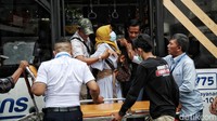 Sejumlah petugas membantu menurunkan WNI dari dalam bus TransJakarta.
