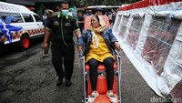 Usai turun dari bus, salah satu WNI menuju Asrama Haji menggunakan kursi roda. Dia tampak didorong oleh petugas.