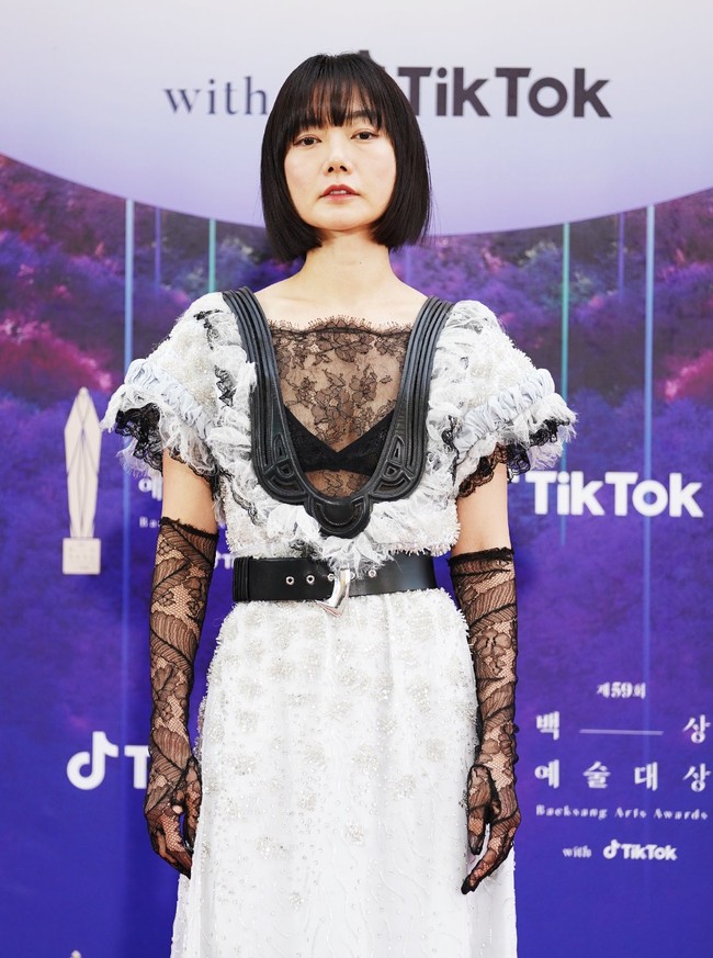 Bae Doona menampilkan selera fashion-nya yang edgy di red carpet Baeksang Awards 2023. Aktris yang khas dengan potongan rambut bob berponi ini mengenakan gaun berdetail smock dan kristal yang dipadankan dengan sarung tangan lace serta belt sebagai aksentuasi pada pinggangnya. Foto: Twitter/@TikTok_Korea, Instagram/@koreadispatch
