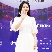 Kim Ji Won tampil elegan dengan gaun bergaya Victorian. Kerah tinggi dengan lengan bervolume menjadikan gayanya lebih anggun. Foto: Twitter/@TikTok_Korea, Instagram/@koreadispatch