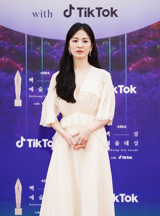 Salah satu aktris yang ditunggu-tunggu di Baeksang Awards, Song Hye Kyo, tampil dengan gaun chiffon pink. Gaun berpotongan A-line itu dirancang dengan garis leher rendah, dan dipercantik detail ruffle pada lengan dan pinggang. Bintang utama ‘The Glory’ ini memilih riasan wajah minimalis bernuansa nude-pink. Foto: Twitter/@TikTok_Korea, Instagram/@koreadispatch