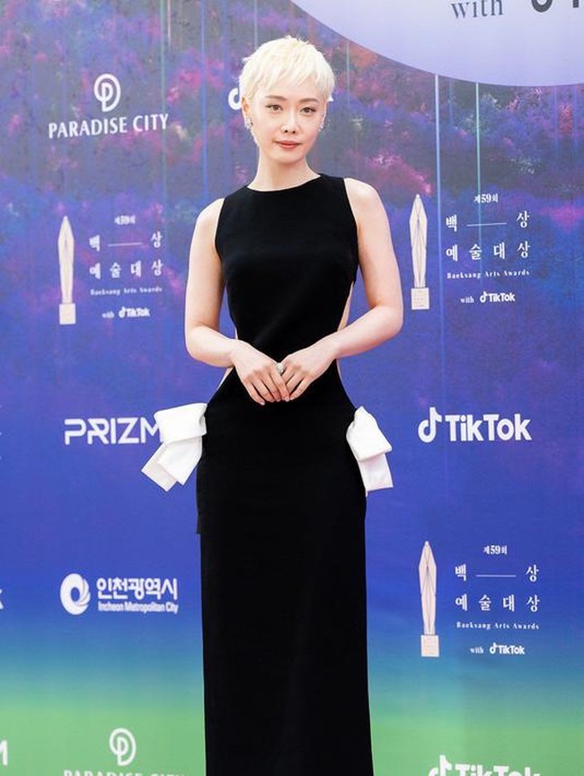 Bintang ‘The Glory’ Kim Hieora berani tampil beda dengan rambut pixie cut yang dicat pirang platinum. Warna rambutnya kontras dengan gaun hitam berpotongan minimalis yang diberi aksen cut-out di bagian belakang dan pita di pinggang. Foto: Twitter/@TikTok_Korea, Instagram/@koreadispatch