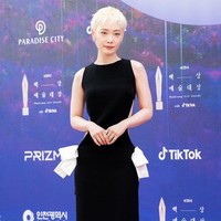 Bintang ‘The Glory’ Kim Hieora berani tampil beda dengan rambut pixie cut yang dicat pirang platinum. Warna rambutnya kontras dengan gaun hitam berpotongan minimalis yang diberi aksen cut-out di bagian belakang dan pita di pinggang. Foto: Twitter/@TikTok_Korea, Instagram/@koreadispatch