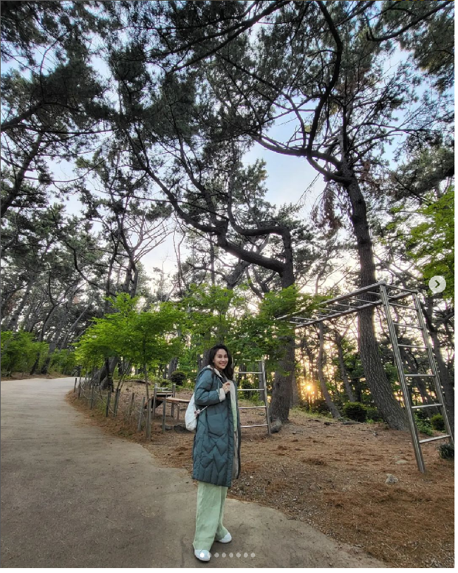 Menikmati taman di kota Busan, Ayu Ting Ting bergaya dengan one set berwarna hijau. Dia memakai jaket parka yang dipadukan dengan sneakers putih dan tas ransel. Foto: Dok. Instagram Ayu Ting Ting