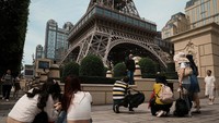 Pengunjung berfoto di depan replika Menara Eiffel di Parisian Macao, resor kasino yang dioperasikan oleh Sands China, saat libur Hari Buruh di Makau, China, 30 April 2023.