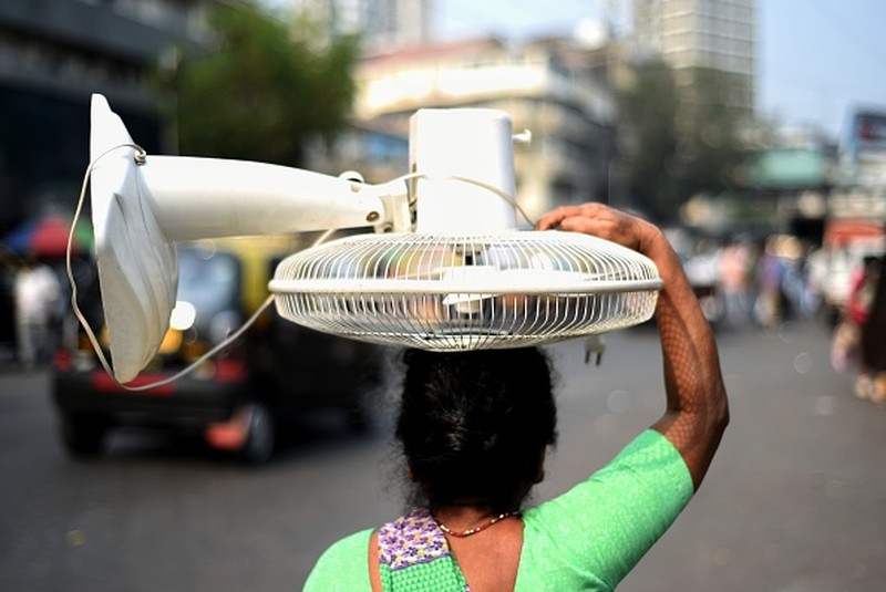 NEW DELHI, INDIA - 2022/06/12: People walk past Akshardham temple on a hot day in New Delhi. Temperatures in the Indian capital soared to above 44 degrees celcius. A heatwave is declared when the maximum temperature is over 40 degrees celsius. (Photo by Pradeep Gaur/SOPA Images/LightRocket via Getty Images)