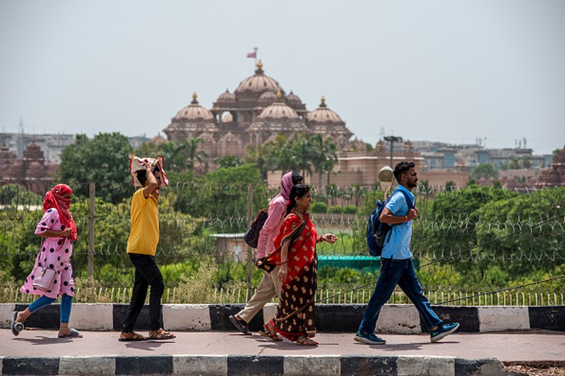 NEW DELHI, INDIA - 2022/06/12: People walk past Akshardham temple on a hot day in New Delhi. Temperatures in the Indian capital soared to above 44 degrees celcius. A heatwave is declared when the maximum temperature is over 40 degrees celsius. (Photo by Pradeep Gaur/SOPA Images/LightRocket via Getty Images)