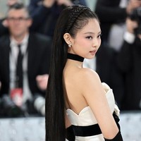Gaun bustier satin yang dikenakannya memiliki aksen pita berhias kamelia putih. Bunga yang sama disematkan pada rambutnya. Jennie pun memakai sarung tangan hitam, stocking, dan heels serasi untuk melengkapi penampilannya. Foto: Getty Images