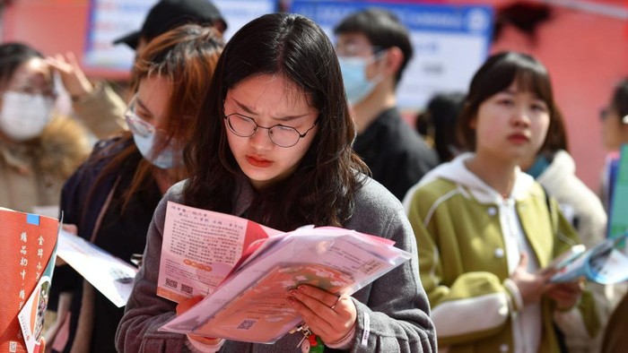 FUYANG, CHINA - MARCH 25, 2023 - Fresh graduates  look for job information at a job fair on the campus of Fuyang Normal University in Fuyang, East Chinas Anhui Province, March 25, 2023. China will graduate a record 11.58 million college students in 2023, according to the Ministry of Education. The employment of college graduates has become a social permasalahan as the economic and social development slows down significantly. (Photo credit should read CFOTO/Future Publishing via Getty Images)