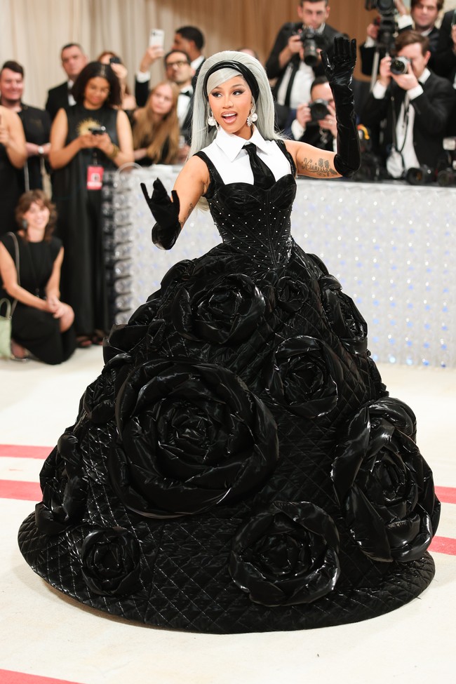 Cardi B mengemas semua elemen khas Chanel dan Karl Lagerfeld dalam satu gaun karya Chenpeng Studio ini. Ada material quilted, dekorasi bunga camellia, dan kemeja putih serta dasi hitam. (Foto: Christopher Polk/WWD via Getty Images)