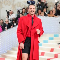 Di tengah dominasi monokromatik hitam-putih, Pedro Pascal tampil beda dengan busana merah menyala keluaran Valentino. Busana andalan bintang ‘Last of Us’ itu terdiri dari kemeja khas Karl dan coat panjang, berikut celana pendek yang memberi twist eksentrik. (Foto: Christopher Polk/WWD via Getty Images)