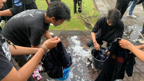 Mahasiswa Unud mencuci jas di depan rektorat memperingati Hardiknas, Selasa (2/5/2023).
