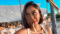 Marion Jola menikmati kelapa muda yang segar di pantai. Foto: Instagram Marion Jola