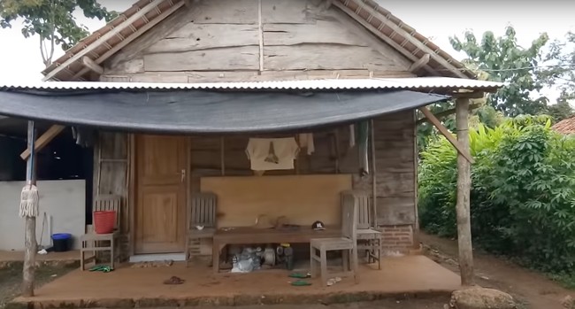 Bagian belakang rumah pun tak kalah sederhana. Ditambah dengan beberapa barang yang berantakan dan jemuran baju, rumah tersebut jadi tampak kumuh. Foto: YouTube/Kromo Chanel