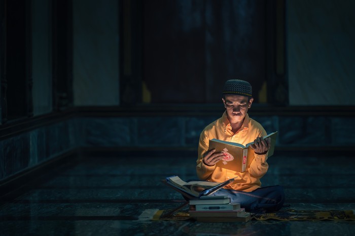 Ilustrasi seorang muslim sedang membaca Al-Quran sebelum tidur.