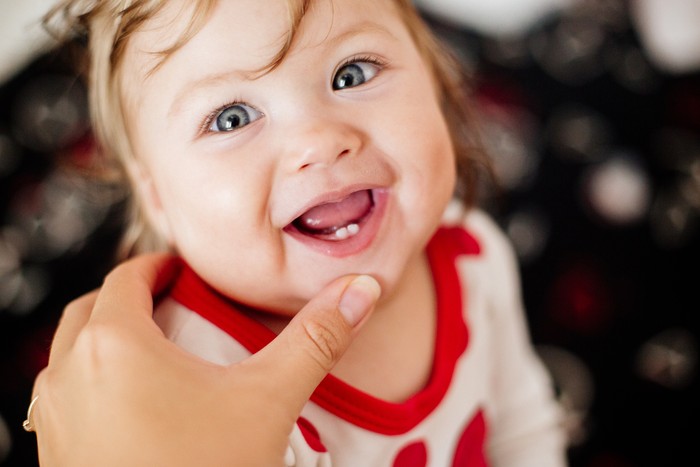 The first teeth of a child. Smile and laugh. Moms hand.
