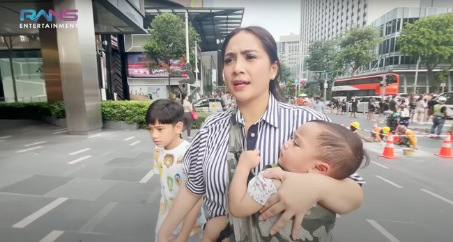 Ketika berjalan-jalan di Singapura Nagitaa juga sempat terlihat momong kedua anaknya sendiri. Sambil menggendong Rayyanza, Nagita menggandeng Rafathar. Foto: YouTube/Rans Entertainment