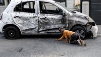 Seorang anak laki-laki mengumpulkan puing-puing mobil yang rusak setelah roket yang diluncurkan dari Gaza mendarat di Sderot, Israel selatan, Selasa (2/5/2023). REUTERS/Amir Cohen.
