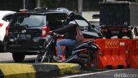 Pengendara motor menerobos barrier untuk berputar balik menjelang jalan masuk ke JLNT Antasari, Jakarta Selatan, Kamis (4/5/2023).