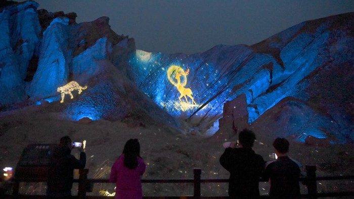 ZHANGYE, CHINA - MAY 03: Tourists watch Danxia landform lit up by colorful lights at Colorful Danxia scenic spot during the May Day holiday on May 3, 2023 in Zhangye, Gansu Province of China. (Photo by Jiumei Danzeng/China News Service/VCG via Getty Images)