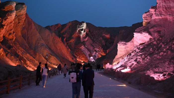 Indahnya Bentang Alam di China Bercahaya Warna-warni ZHANGYE, CHINA - MAY 03: Tourists watch Danxia landform lit up by colorful lights at Colorful Danxia scenic spot during the May Day holiday on May 3, 2023 in Zhangye, Gansu Province of China. (Photo by Jiumei Danzeng/China News Service/VCG via Getty Images)