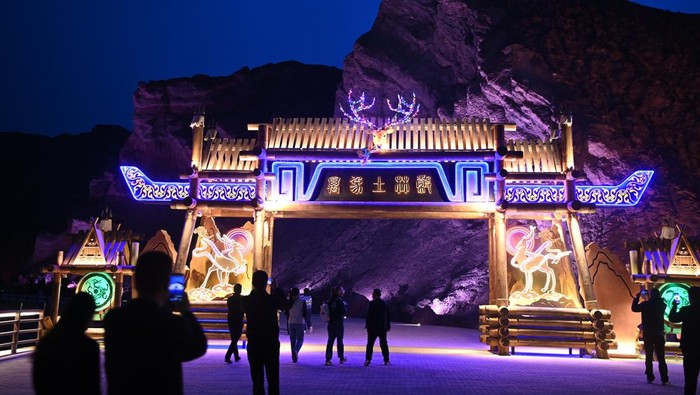 ZHANGYE, CHINA - MAY 03: Tourists watch Danxia landform lit up by colorful lights at Colorful Danxia scenic spot during the May Day holiday on May 3, 2023 in Zhangye, Gansu Province of China. (Photo by Jiumei Danzeng/China News Service/VCG via Getty Images)