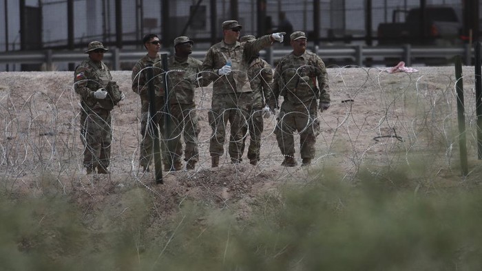 Members of the Texas National Guard install a barbed-wire barrier on the border between El Paso, Texas and Ciudad Juárez, as seen from Ciudad Juárez, Mexico, Wednesday, May 3, 2023. The Biden administration has requested 1,500 troops for the U.S.-Mexico border amid an expected migrant surge following the end of pandemic-era restrictions. (AP Photo/Christian Chavez)