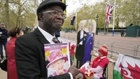 Penggemar kerajaan Chris Imafidon menyelamatkan tempatnya di sepanjang rute penobatan Raja di The Mall di London. AP/Frank Augstein  