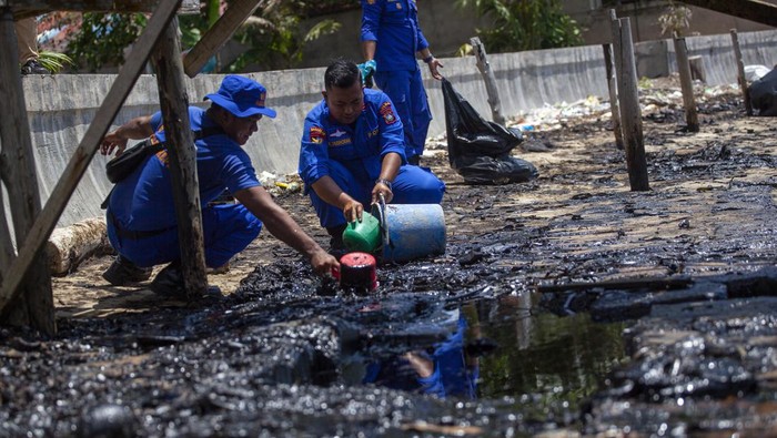 Petugas Dit Polair Polda Kepri  mengangkat wadah berisi limbah minyak hitam saat membersihkan tepi Pantai Melayu, Batu Besar, Batam, Kepulauan Riau, Kamis (4/5/2023). Tim gabungan dari berbagai instansi masih melakukan penyelidikan dan upaya pembersihan kawasan pantai tersebut dari limbah minyak hitam. ANTARA FOTO/Teguh Prihatna/foc.