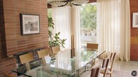 Bergeser ke ruangan yang lain, ada ruang makan yang didesain untuk mencukupi kebutuhan cahaya. Meja kaca dengan jendela yang besar membuatnya menyantap makanan sambil memandangi halamannya. Foto: YouTube/Architectural Digest
