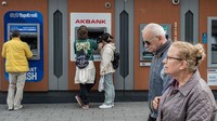 Warga menggunakan anjungan tunai mandiri (ATM) di Istanbul, Turki, Rabu (3/4/2023).
