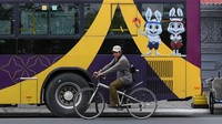 Seorang pria mengendarai sepedanya di depan bus bermaskot dan berlogo Pesta Olahraga Asia Tenggara (SEA Games). Nhac Nguyen/AFP/Getty Images  
