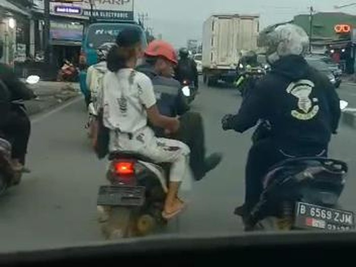 Seorang pengendara motor terlibat cekcok dengan pengawal ambulans di Jalan Raya Parung-Bogor. Pemotor itu sampai menendang pengawal ambulans. (Tangkapan layar video viral)