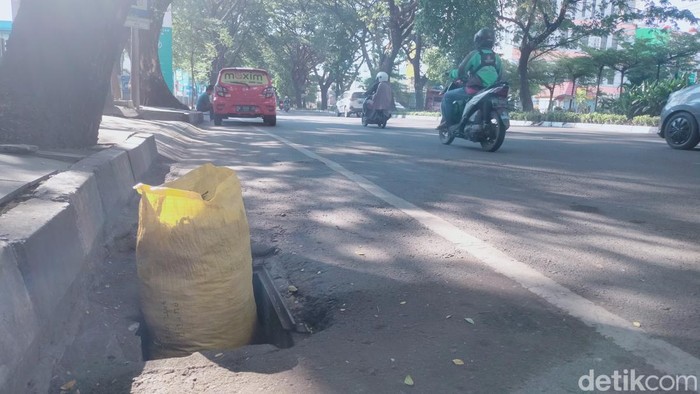 Lubang di Jalan Hertasning bahayakan pengendara ditutup dengan karung dan ban.