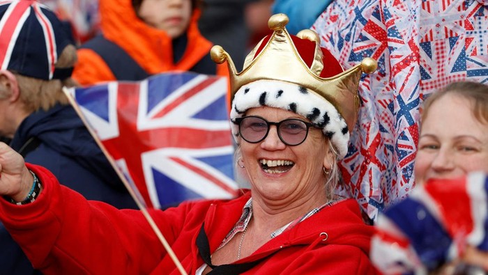 Warga menyambut antusias penobatan Raja Charles III. Bahkan sebagian mereka menyaksikan prosesi penobatan dengan memakai topeng Raja Charles dan Ratu Camilla.