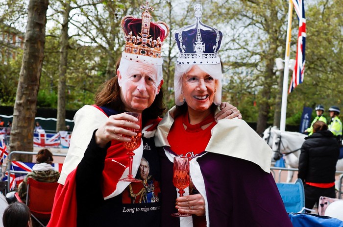 Warga menyambut antusias penobatan Raja Charles III. Bahkan sebagian mereka menyaksikan prosesi penobatan dengan memakai topeng Raja Charles dan Ratu Camilla.