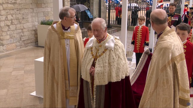 Dalam acara yang dapat secara langsung disaksikan warga dunia, Raja Charles III masuk dengan jubah dengan perpaduan warna putih dan hitam. Dilaporkan bahwa busana tersebut pernah dikenakan kakeknya, Raja George VI, saat acara penobatannya. Charles pun ditemani oleh calon penerusnya, Pangeran George, yang bertugas memegang ekor dari jubahnya.Foto: YouTube The Royal Family
