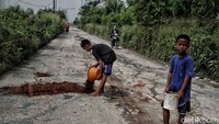 Sejumlah warga menambal jalan yang rusak dengan tanah.