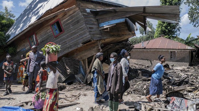 People walk next to houses destroyed by the floods in the village of Nyamukubi, South Kivu province, in Congo Saturday, May 6, 2023. The death toll from flash floods and landslides in eastern Congo has risen according to the governor and authorities in the country's South Kivu province. (AP Photo/Moses Sawasawa)