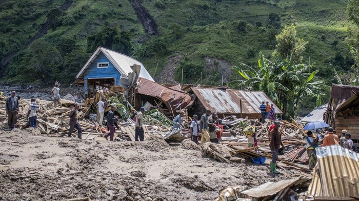 People walk next to houses destroyed by the floods in the village of Nyamukubi, South Kivu province, in Congo Saturday, May 6, 2023. The death toll from flash floods and landslides in eastern Congo has risen according to the governor and authorities in the country's South Kivu province. (AP Photo/Moses Sawasawa)