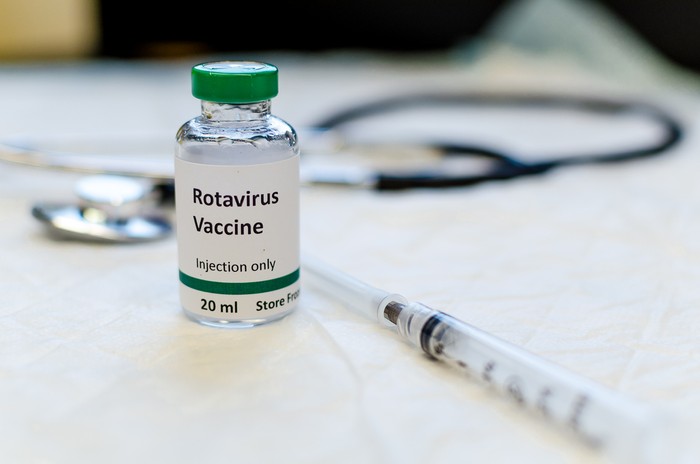 Fake rotavirus vaccine vial with syringe and stethoscope at the background