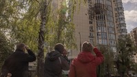 Warga melihat bangunan apartemen yang rusak di Kyiv, Ukraina, Senin (8/5/2023).