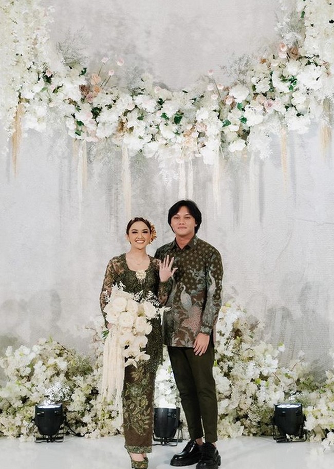 Keduanya tampil kompak mengenakan busana hijau tua. Mahalini mengenakan kebaya hijau dengan sarung batik yang senada dengan kemeja Rizky. Foto: dok. Instagram/@thebridestory