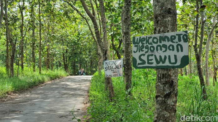Spanduk bertulisan welcome to jeglongan sewu di jalan rusak Giring-Singkil, Paliyan, Gunungkidul, DIY, Senin (8/5/2023).