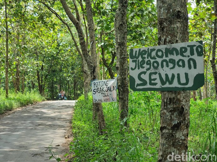 Spanduk bertulisan welcome to jeglongan sewu di jalan rusak Giring-Singkil, Paliyan, Gunungkidul, DIY, Senin (8/5/2023).